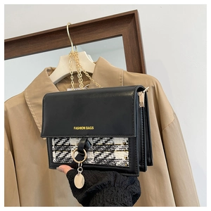 Detail of checkered fabric and black leather on a handbag with gold chain strap