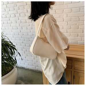 Chic cream leather baguette bag shown as a shoulder style in a cozy interior setting