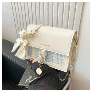 Detail of a beige and blue woven crossbody bag with gold chain and silk scarf handle