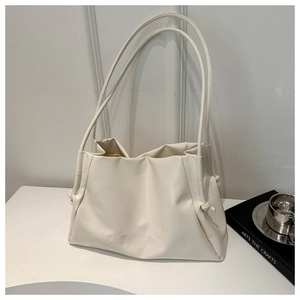 Detailed macro view of cream-colored pleated leather tote bag with embossed letter logo