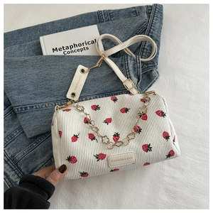 Detail of white corduroy pillow bag with strawberry print and gold flower chain strap