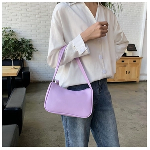 Purple faux leather baguette bag worn by model with casual white shirt and jeans outfit