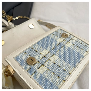 Detail view of the blue and white tweed crossbody bag with golden magnetic clasp