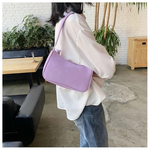 Minimalist light purple baguette bag worn over the shoulder showing actual size and scale