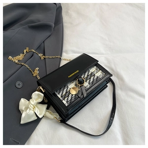 Detail view of tweed patchwork shoulder bag with gold chain and white satin bow accent