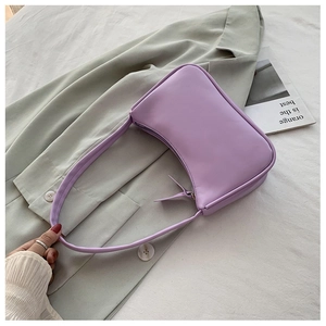 Close-up of a purple crescent underarm bag in smooth PU leather on a green blazer