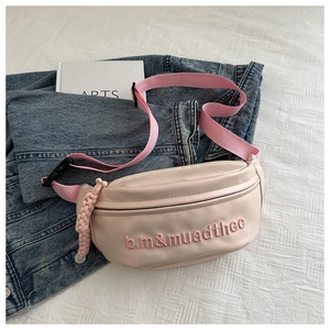 Détail du sac banane en cuir PU beige avec broderie rose et sangle en nylon rose