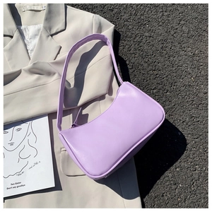 Close-up of minimalist lavender leather shoulder bag on a beige blazer outdoors