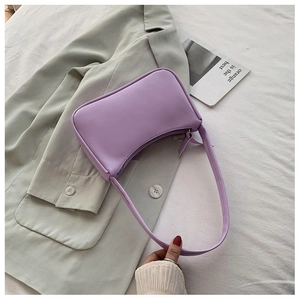 Close-up of light purple baguette shoulder bag in smooth faux leather on a green blazer
