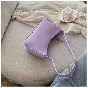 Close-up of light purple minimalist underarm bag on a textured fabric surface