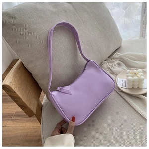Close-up of light purple leather underarm bag on soft cushion with elegant decor