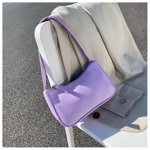 Lavender purple baguette bag hanging on a beige blazer during an outdoor photoshoot