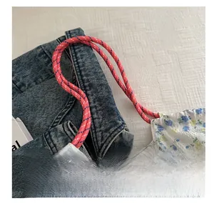 Detail view of pink woven rope shoulder strap on floral print cotton tote bag