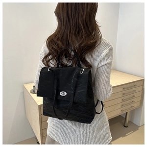 Detail of black backpack showing crinkled texture fabric and silver swivel metal lock