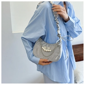 Detail of silver crescent bag with pearl bow chain and metallic pleated strap for women