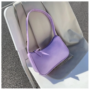Close-up of lilac purple faux leather underarm bag with zipper on a white outdoor chair