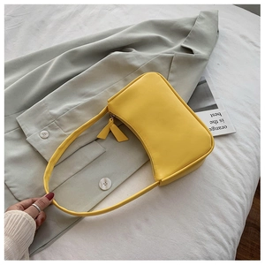 Detail shot of bright yellow baguette shoulder bag on aesthetic fabric background