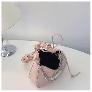 Detail of light pink dumpling bag featuring trendy ruched handle and elegant pearl chain