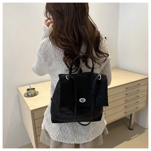 Detail of black nylon backpack with silver twist lock and adjustable straps on model