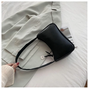 Minimalist black faux leather baguette bag with zip closure on a neutral blazer background
