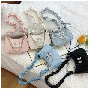Detail of colorful ruched hobo bags with pearl chains and silver metal bow accents