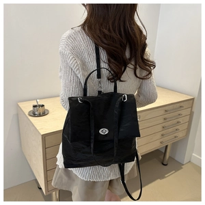 Detail of black wrinkled texture backpack featuring a silver metal twist lock closure