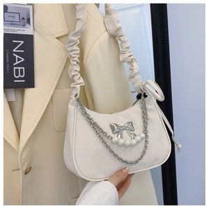 Close-up of white croissant bag with pearl chain and silver bow metal detail