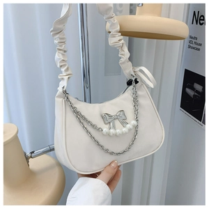 Detail of white dumpling bag with silver bow accent and elegant pearl chain strap