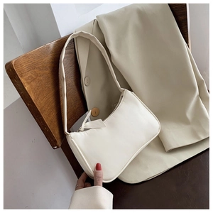 French style minimalist cream white PU baguette bag hanging on a wooden chair