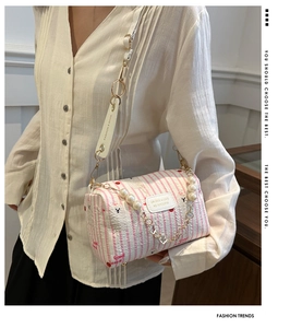 Detail der rosa-weiß gestreiften Zylindertasche mit Perlenkette und Bärenmustern