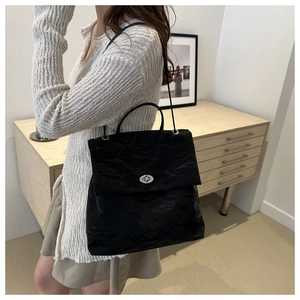 Détail du sac à main en cuir froissé noir avec fermoir rotatif argenté et bandoulière