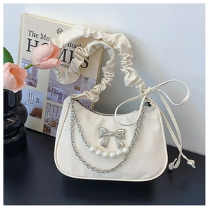 Detail of cream white dumpling bag with silver bow charm, pearl chain and ruched handle