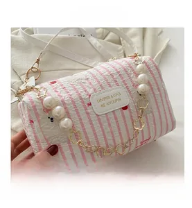 Détail du sac cylindre à rayures florales avec chaîne en perles et étiquette cuir