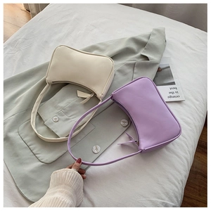 Detail view of stylish minimalist underarm bags in cream and lilac with zipper design