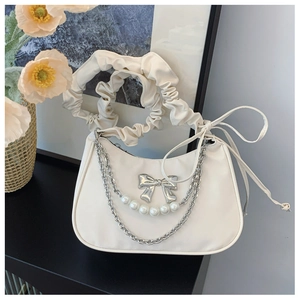 Detail of white crescent bag featuring pearl chain and metallic bow accents