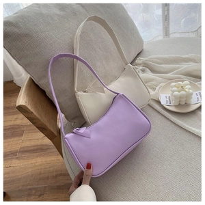 Detail of purple and beige PU leather baguette underarm bags on a minimalist sofa