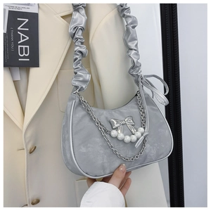 Detailed view of silver crescent bag with beaded chain and metallic bow decoration