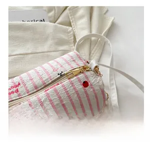 Détail du zip doré lisse et de la perle sur le sac cylindrique imprimé cerises