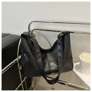 Detail of a large black leather tote bag with geometric color-block paneling and gold hardware