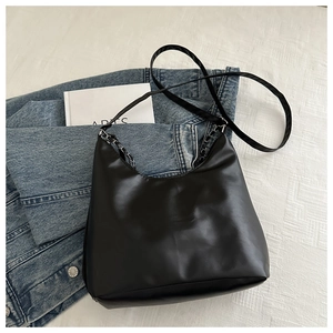 Detail of black Hobo bag with mixed leather and silver chain strap on white fabric