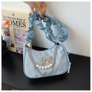 Detail of light blue pleated handbag with silver bow, metal chain and pearl ornaments