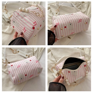 Vue détaillée du sac cylindrique à rayures roses avec chaîne de perles et imprimé fleuri