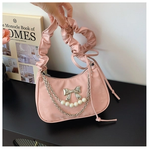 Close-up of pink pleated shoulder bag with pearl chain and silver bow detail