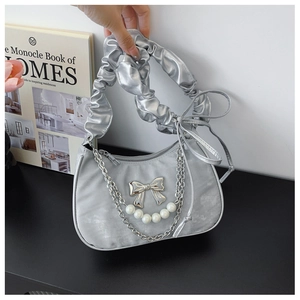 Detailed close-up of a silver dumpling bag featuring a pearl chain and metallic bow accent