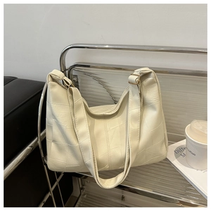 Detail of a large cream patchwork tote bag with gold hardware and wide shoulder strap