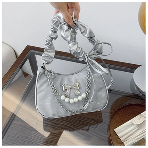 Detail of silver pleated shoulder bag with pearl accents and metal bow charms