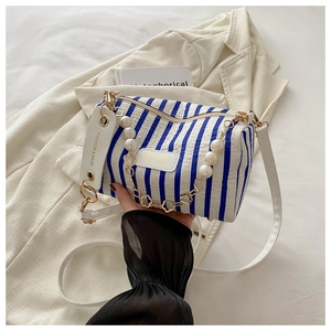 Detail der blau-weiß gestreiften zylindrischen Tasche mit dekorativem Perlenhenkel