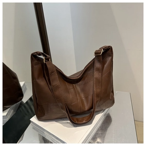 Detailed close-up of dark brown patchwork leather tote bag featuring sleek metallic buckle