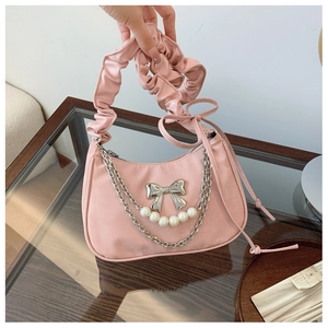Detailed shot of pink pleated shoulder bag with silver bow and pearl chain handle