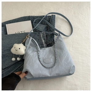 Macro view of light blue wrinkled fabric handbag with silver chain and cloud charm